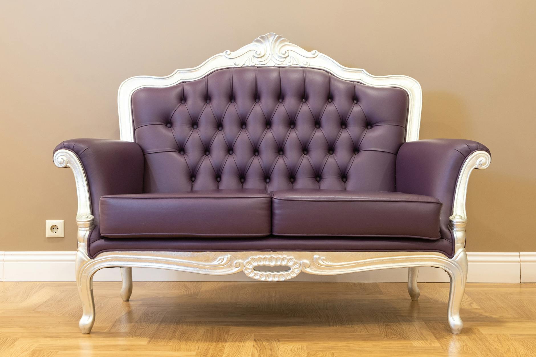 Brązowa pikowana skórzana sofa vintage z ozdobną ramą w salonie