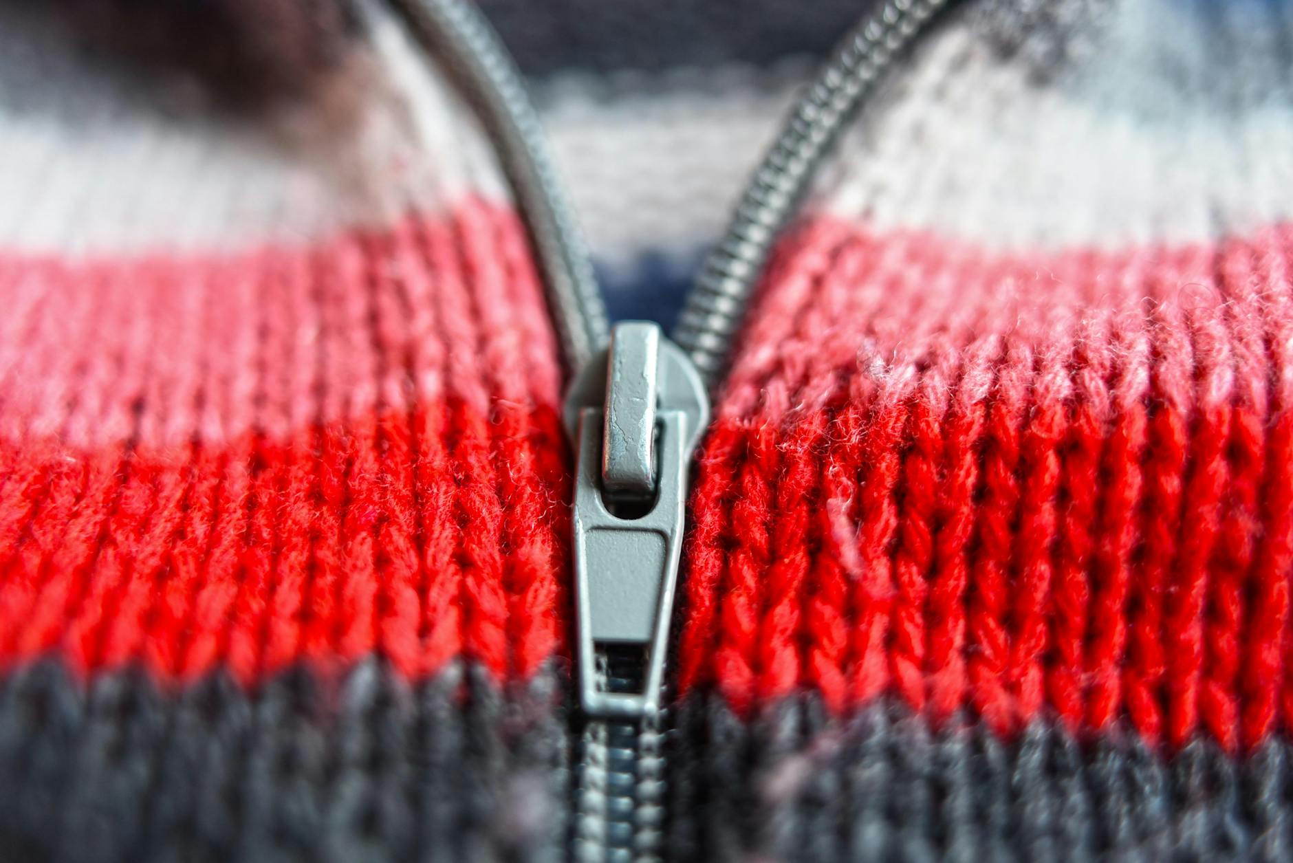 Metalowy zamek błyskawiczny na czerwono-granatowej dzianinie w paski