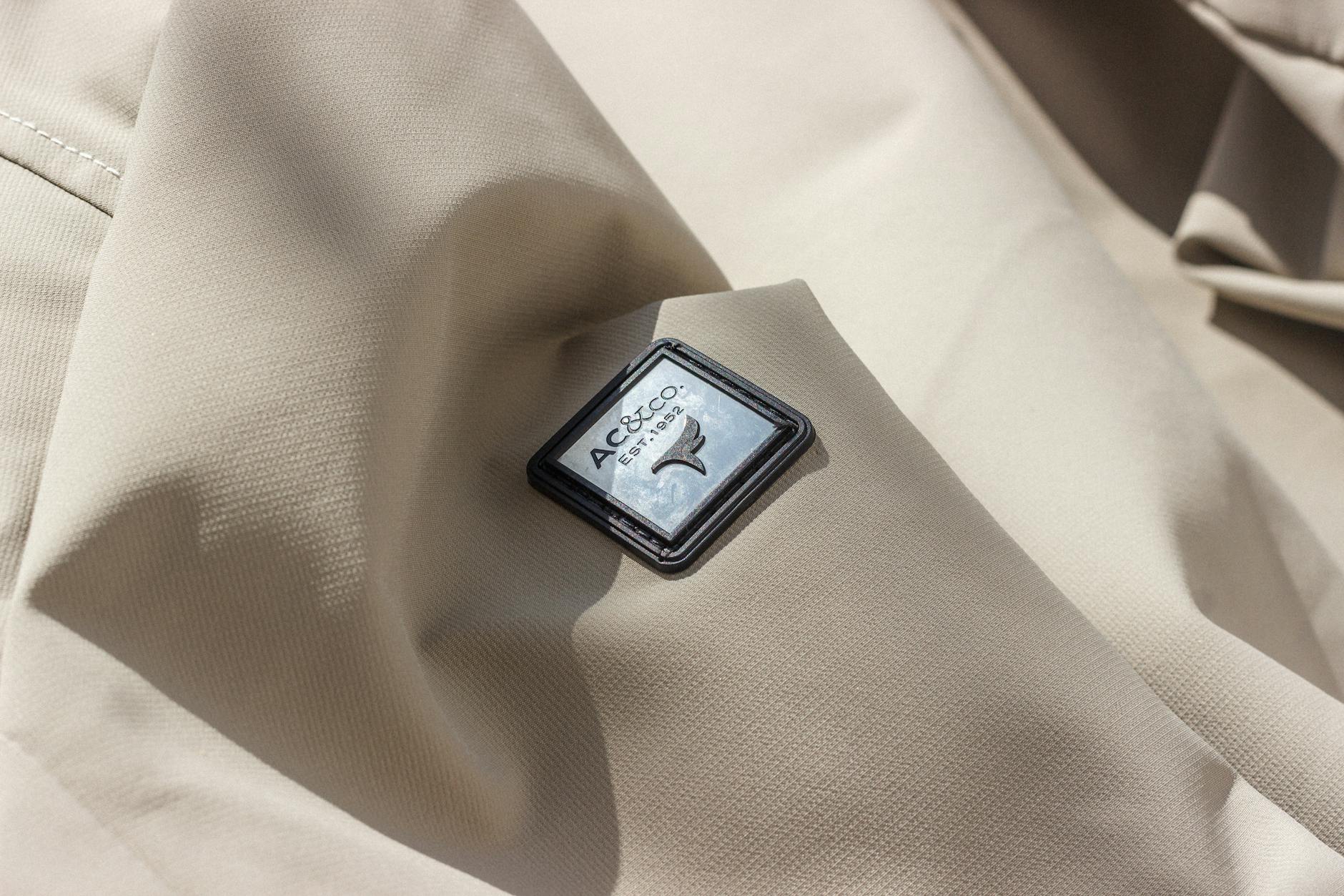 Zbliżenie beżowej tkaniny z logo AC&Co i wyraźną strukturą materiału