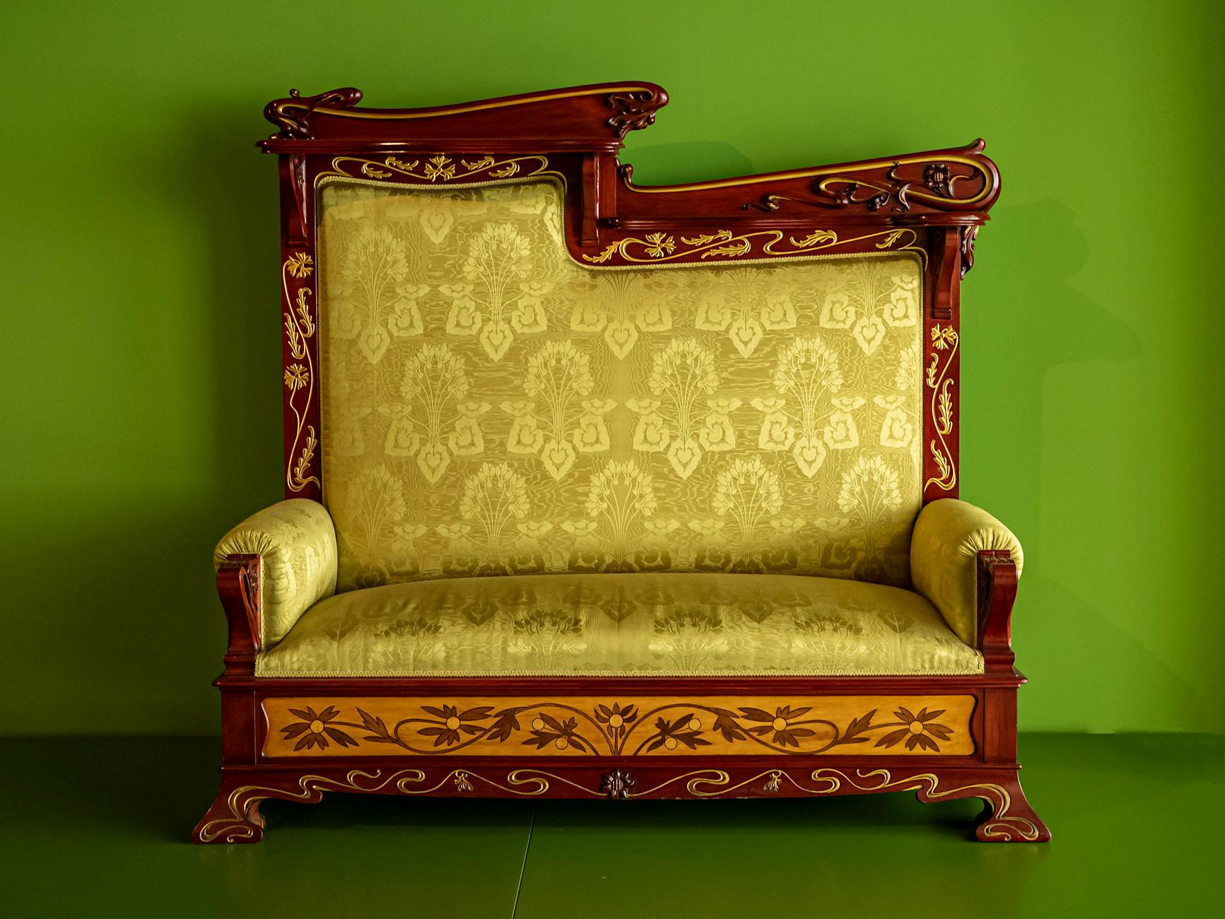 Zdobiona, vintage sofa z misternym wzorem na tle intensywnej zieleni