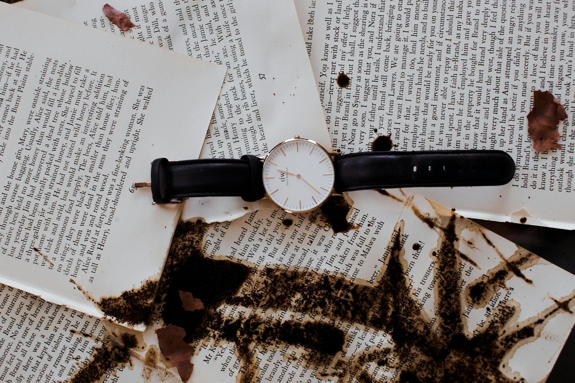 Zegarek na tle książki z plamami kawy na kartkach