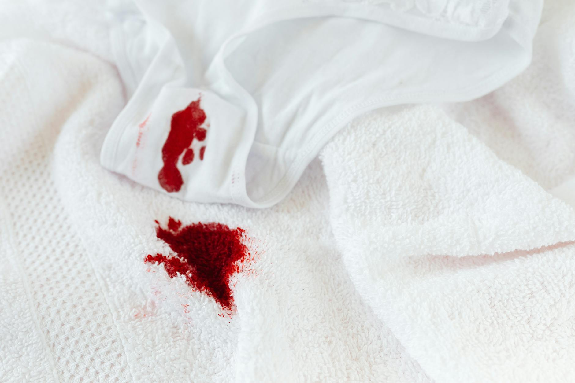 Białe majtki i ręcznik z widocznymi plamami krwi menstruacyjnej