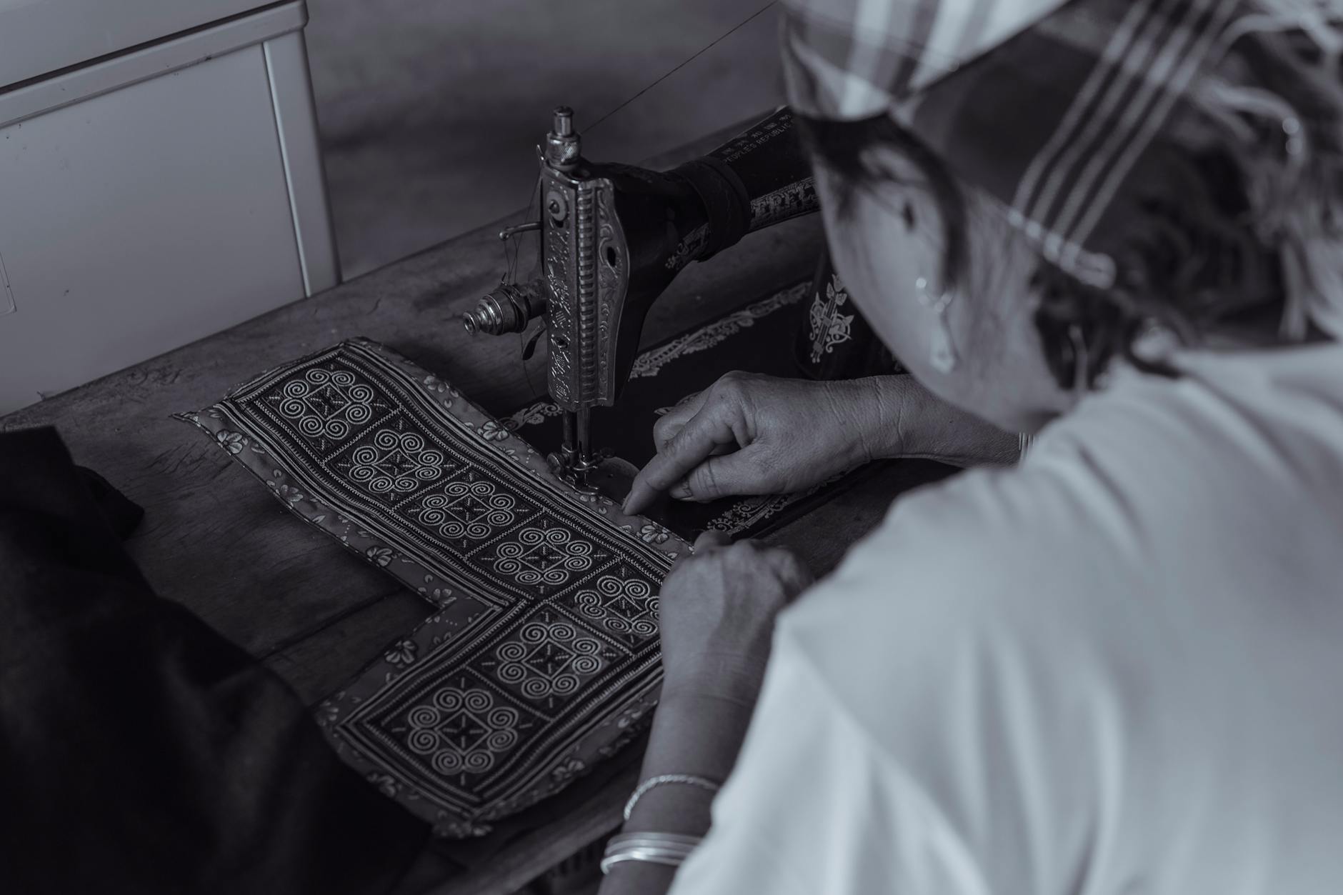 Kobieta szyje na starej maszynie, tworząc wzór na dzianinie