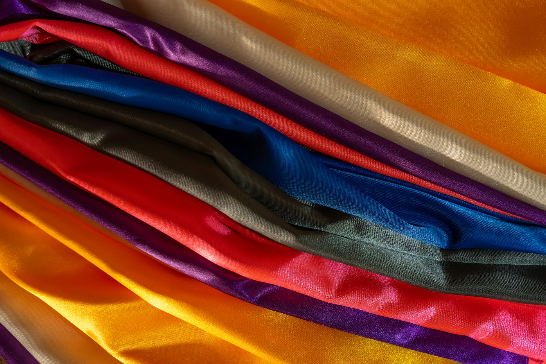 Wielobarwne połyskujące tkaniny satynowe rozwieszone obok siebie