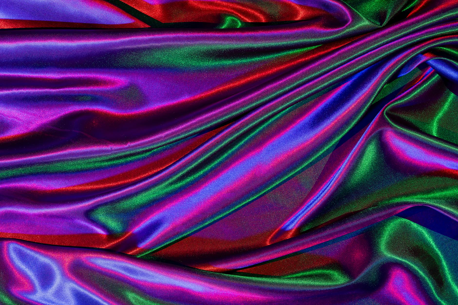Zbliżenie kolorowej, połyskującej tkaniny satynowej o falującej fakturze