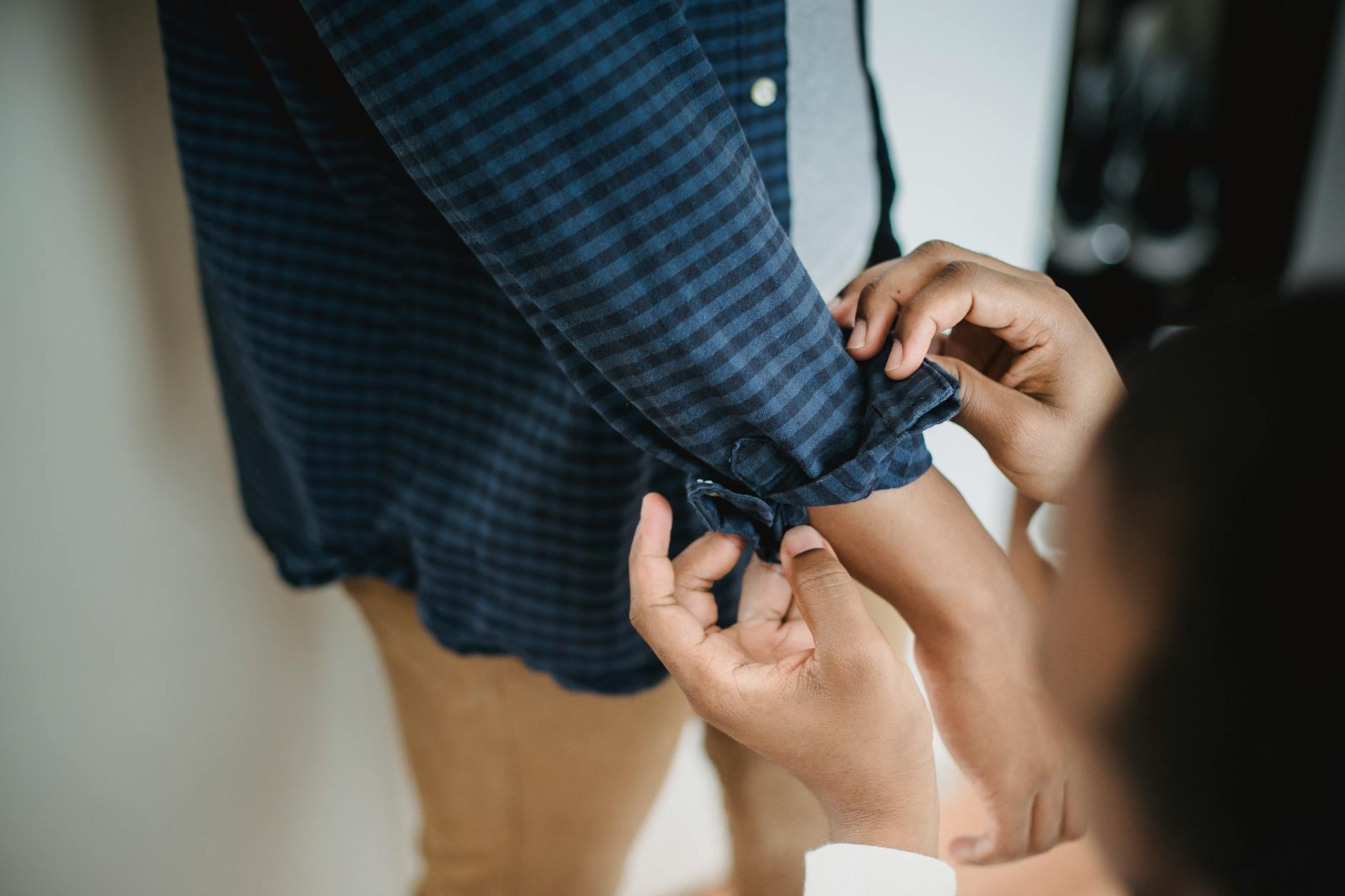 Zbliżenie na osobę podwijającą rękaw koszuli w kratę