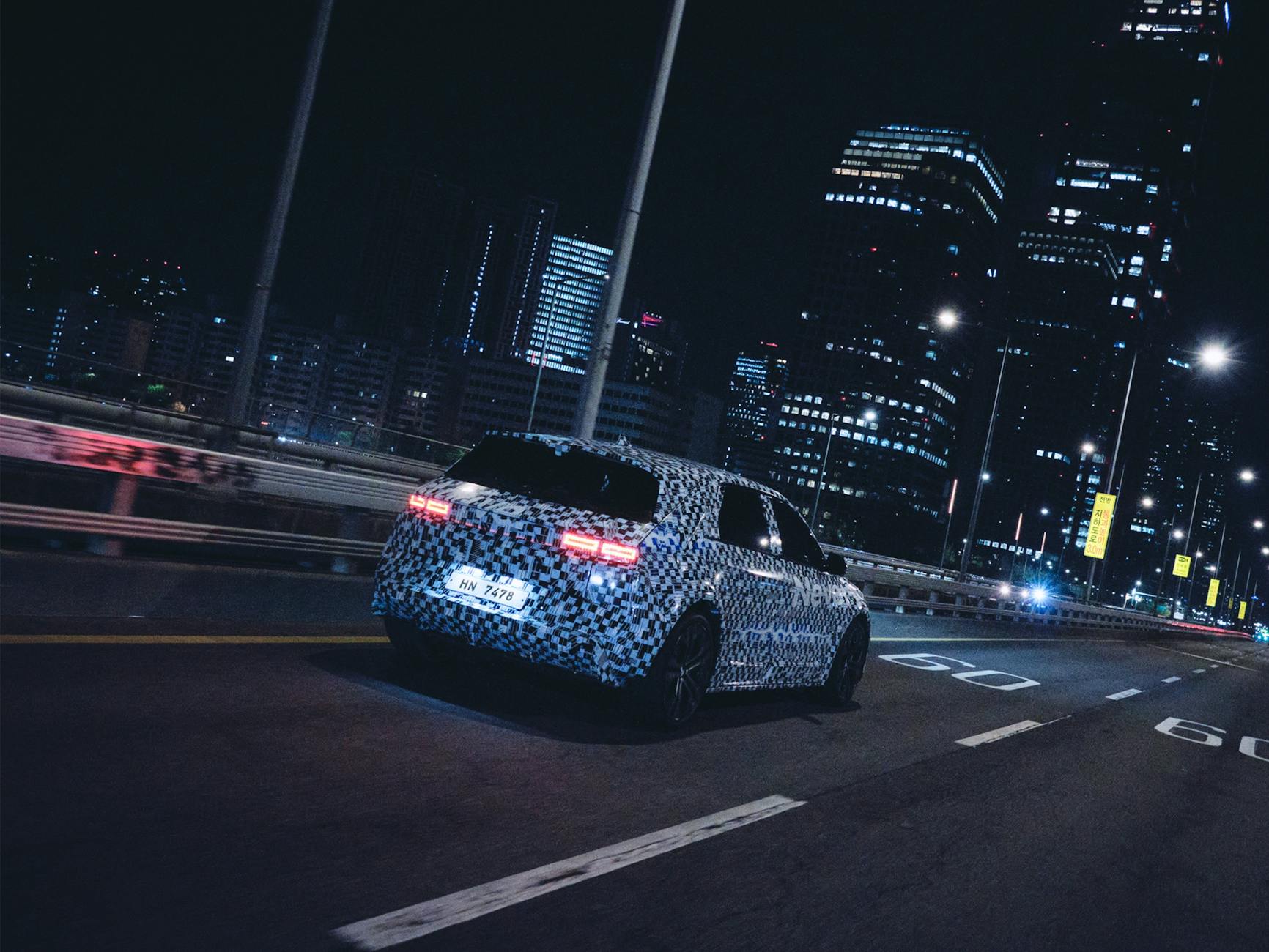 Elektryczny samochód w kamuflażu jedzie nocą przez oświetlone miasto