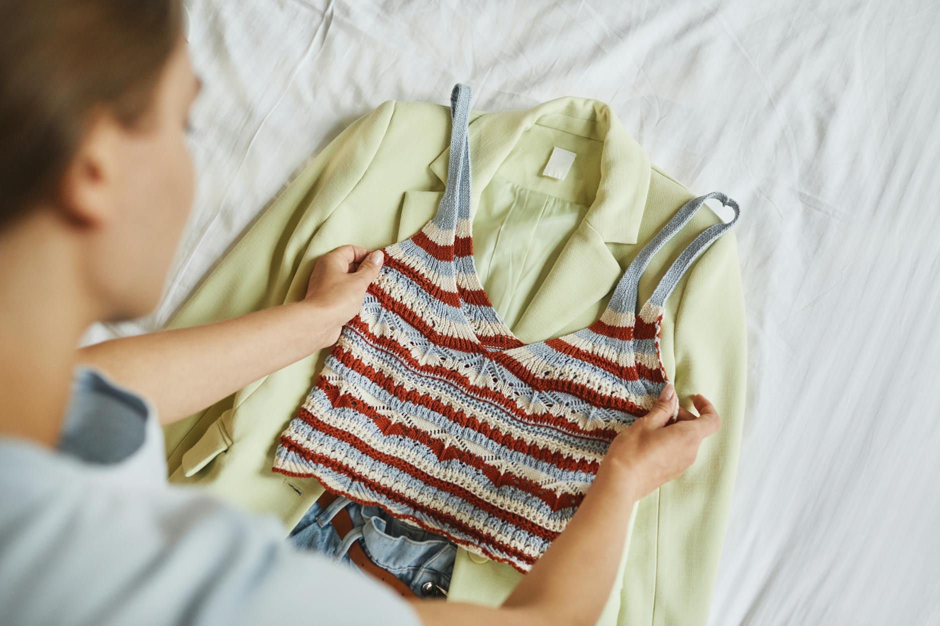 Kobieta układa na łóżku zestaw z żakietem i dzianinową bluzką