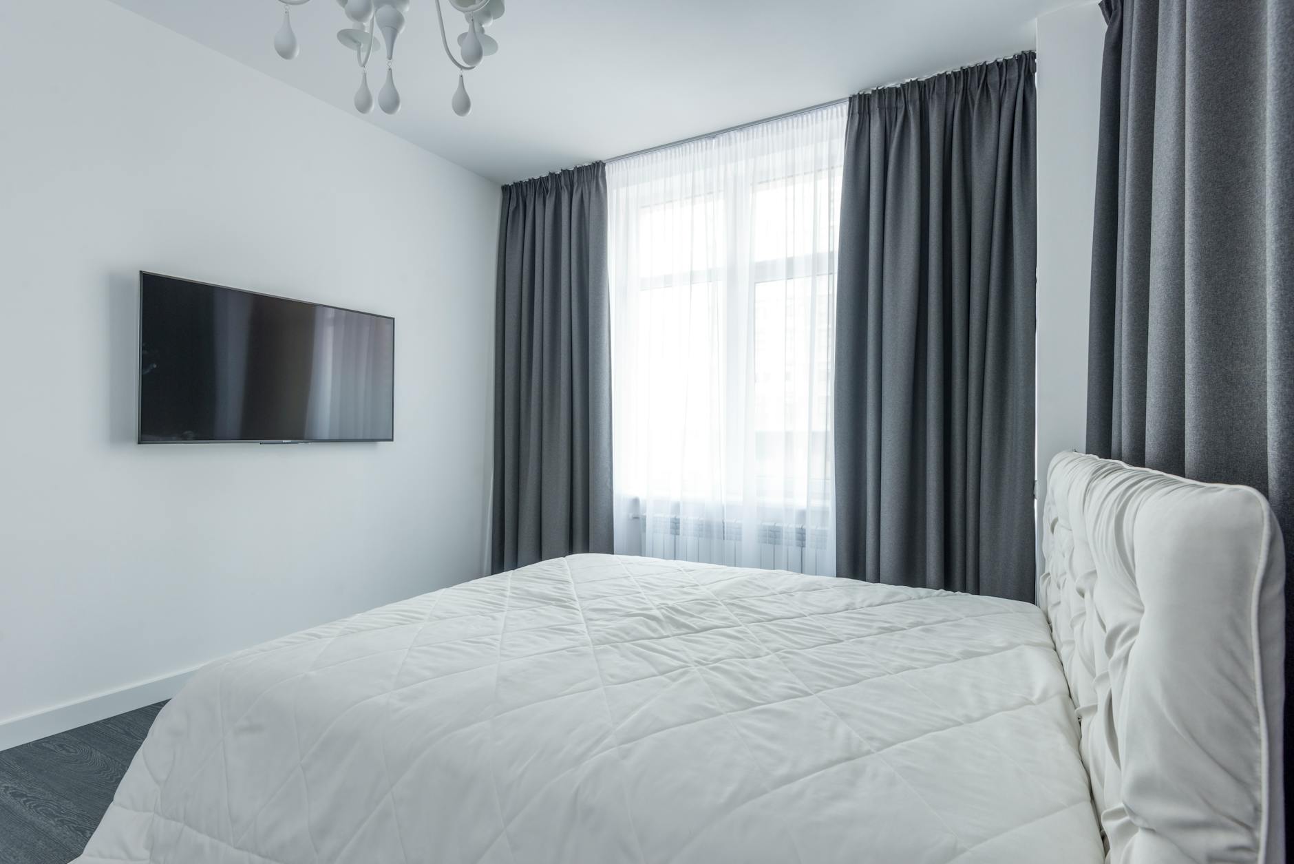 Nowoczesna sypialnia z minimalistycznym wystrojem i eleganckimi zasłonami