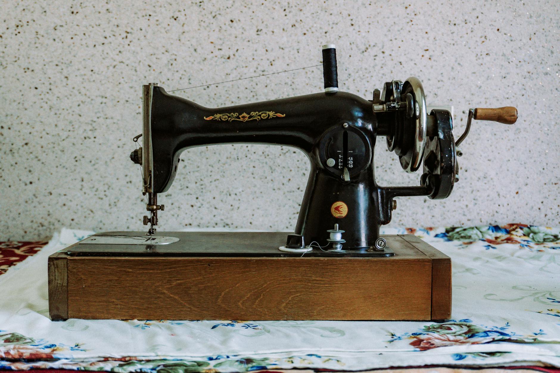 Zabytkowa maszyna do szycia stojąca na kwiecistym obrusie