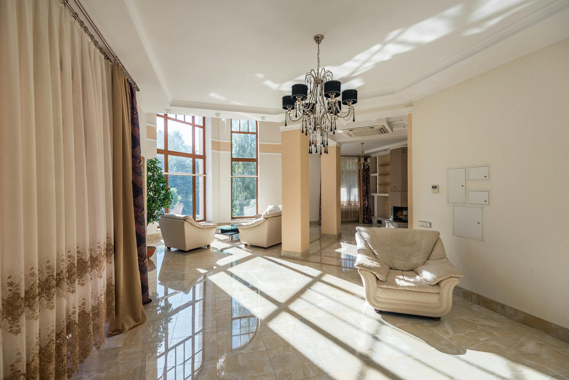 Nowoczesny salon z dużymi oknami, firanami i eleganckim żyrandolem