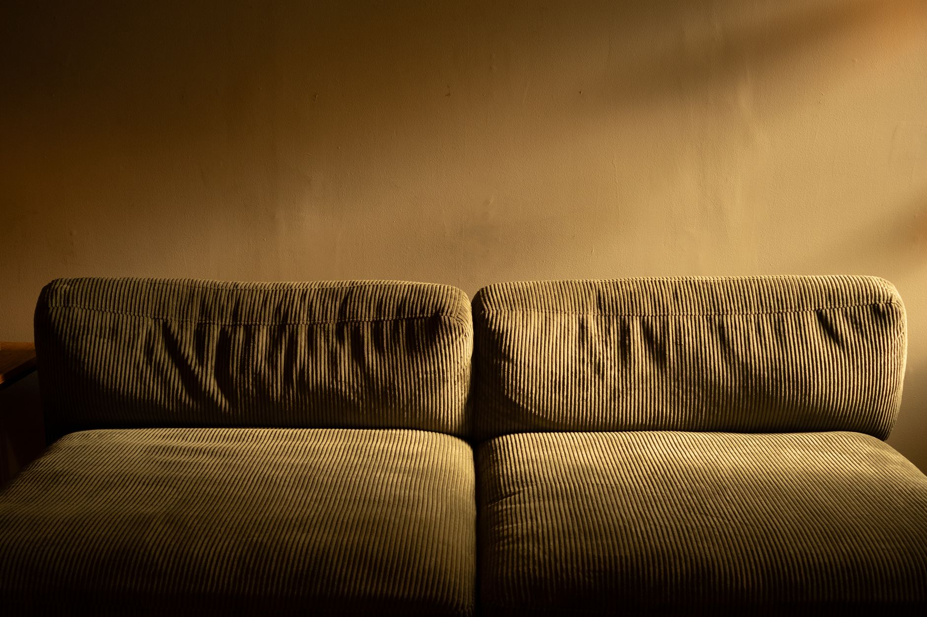 Pluszowa sofa z sztruksowym obiciem w ciepłym, nastrojowym oświetleniu